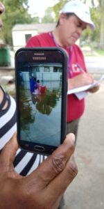 Woman shows photo of family carrying her daughter through flood waters